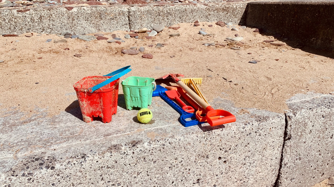Bucket and spades left abandoned on the beach after use.