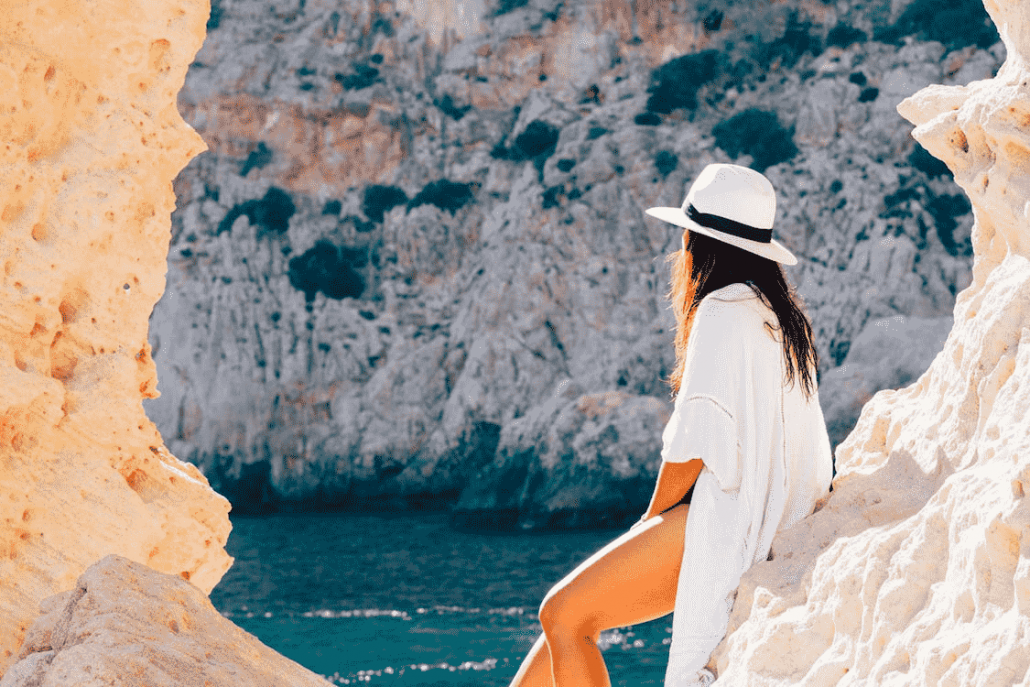 woman with hat looking out over quiet bay during shoulder season