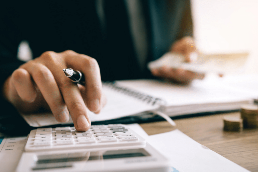 person with pen in hand using calculator