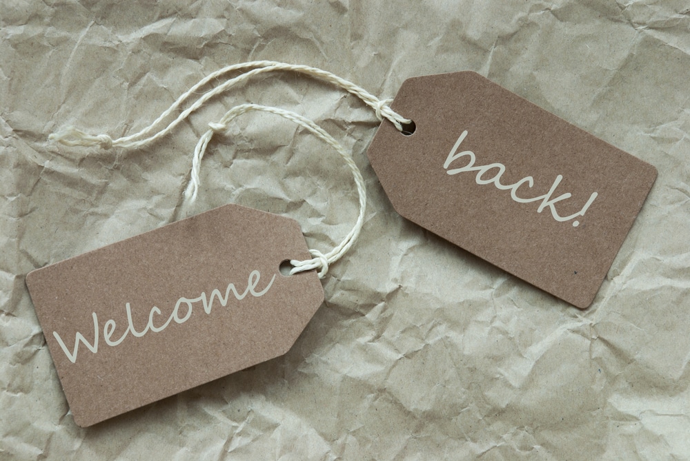 Two paper tags with the words 'Welcome' and 'back!' on crumpled brown paper