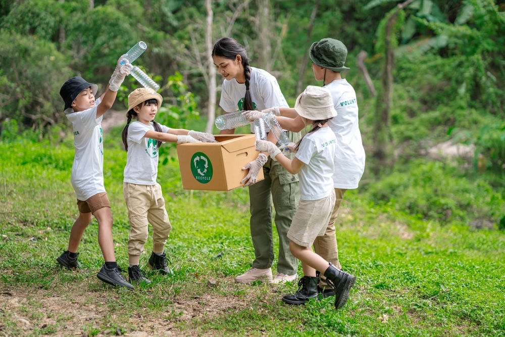 Children volunteering for recycling outdoors with an adult