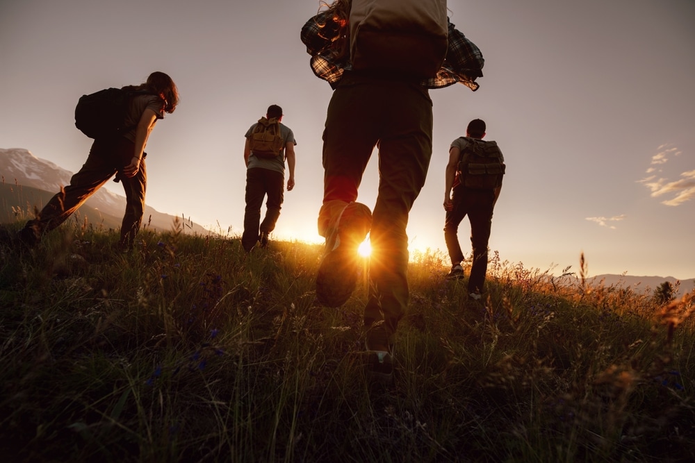 Hikers walking through a field at sunset