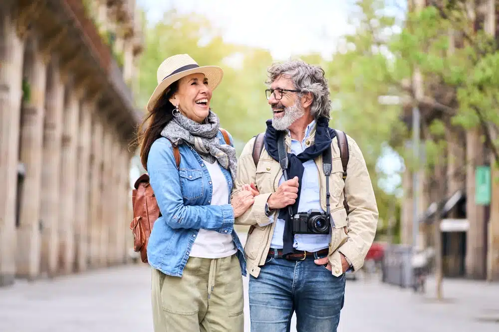 Happy mature couple with a camera laughing on a city street